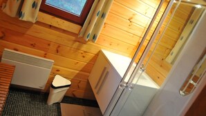 A wooden cabin bathroom with a window, a radiator, a sink, and a shower area. - Apartment in Belgium Near Scenic Spots (Viroinval)