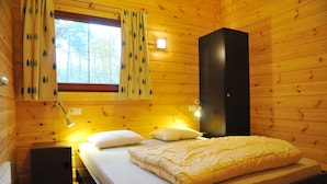 A wooden cabin room with a bed, a nightstand, a wardrobe, and a window with curtains. - Apartment in Belgium Near Scenic Spots (Viroinval)