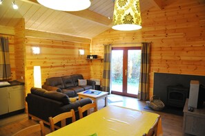 En stuga byggd av timmer med ett vardagsrum, matplats, kök och öppen spis.