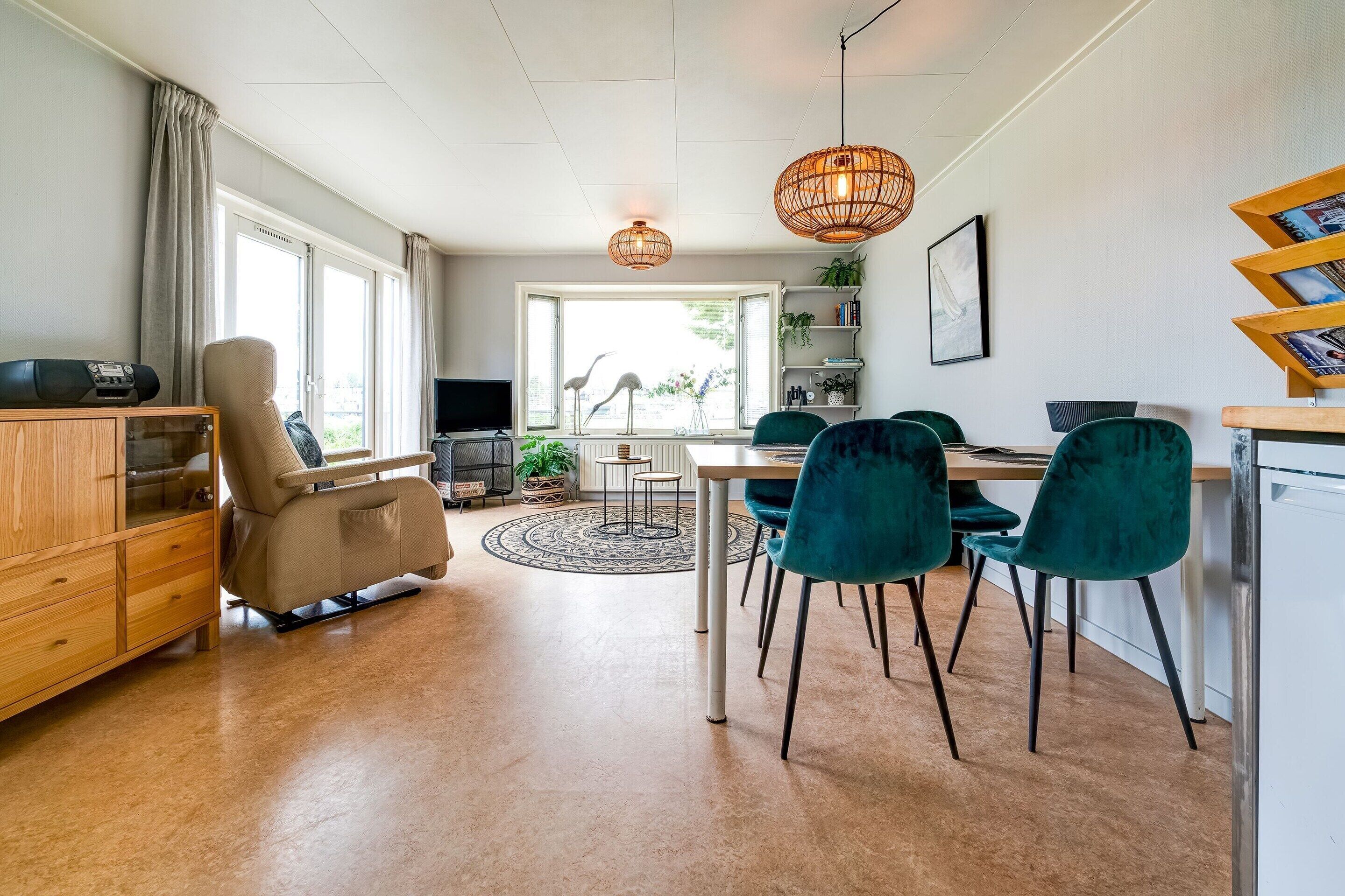 A modern living room with a sofa, a dining table with chairs, a TV, and a bookshelf.