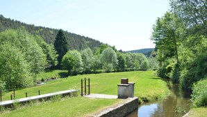 Un paysage paisible au bord de la rivière, avec un mur de pierre et un petit pont.