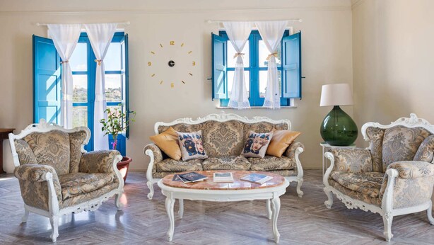 A living room with a patterned sofa set, a round coffee table, and a large green vase. - Belvilla by OYO Casale di Benedetto (Caltagirone)