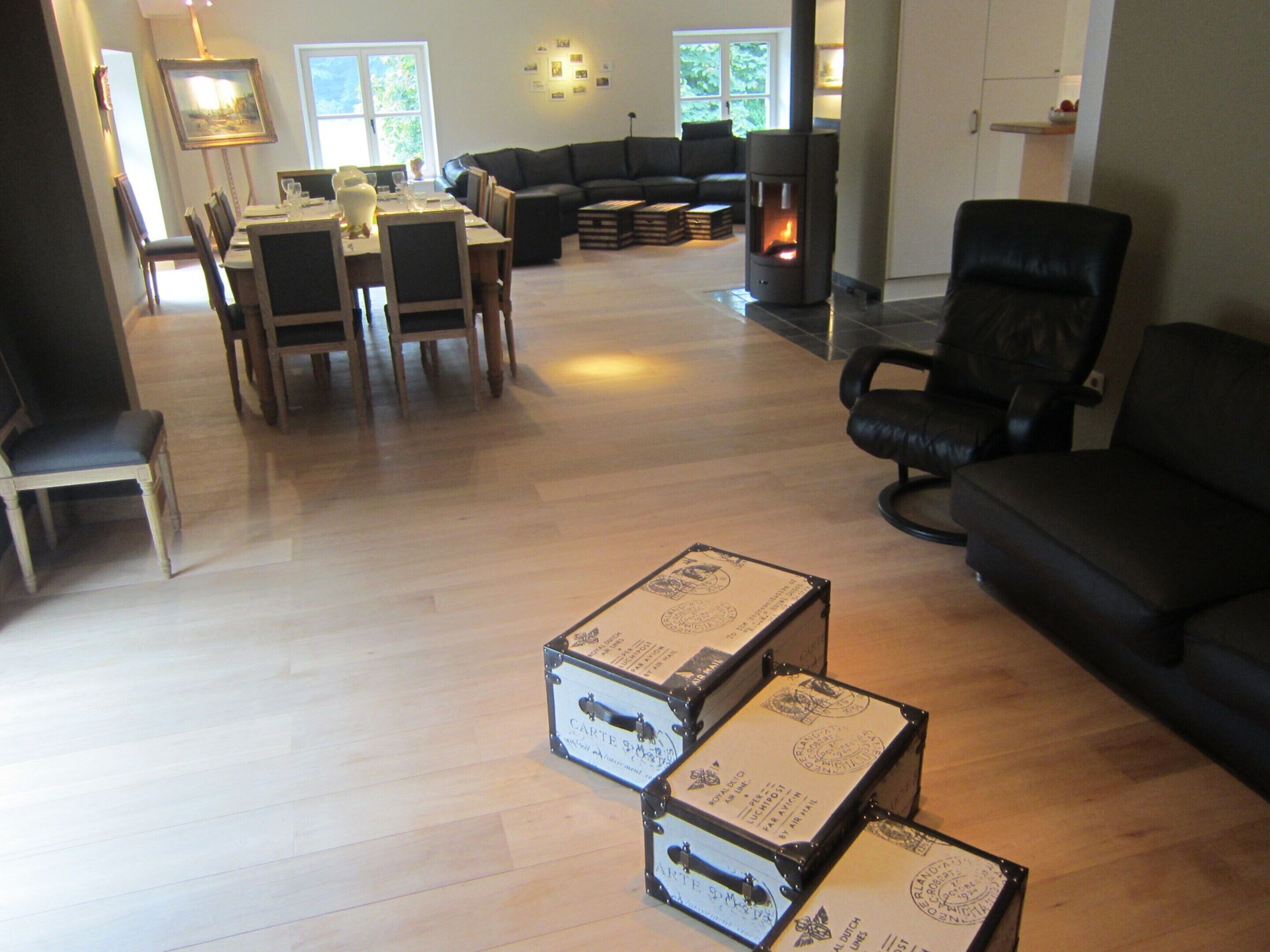 A spacious living room with a dining area, a fireplace, and two large suitcases on the floor.