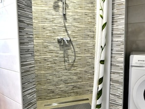 A shower with a modern design, featuring a patterned wall and a showerhead.