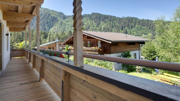 A wooden balcony with a view of a mountain and a building in the background.