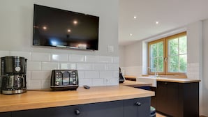 A modern kitchen with a flat-screen TV, a coffee maker, and a toaster on the counter.