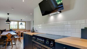 A modern kitchen with a built-in stove, a large window, and a dining area with wooden furniture.