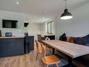 A modern kitchen with a wooden dining table, black cabinets, and a black trash bin. - Chalet in Hollersbach / Salzburg Near ski Area (Hollersbach im Pinzgau)