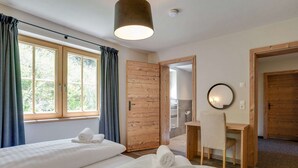A hotel room with two beds, a desk, a mirror, and a view of the outdoors.