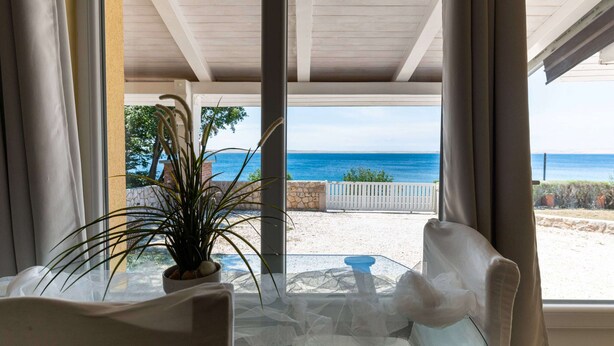 A room with a view of the beach, a table with chairs, and a potted plant. - Captivating Holiday Home in Tribanj near Sea (Starigrad)