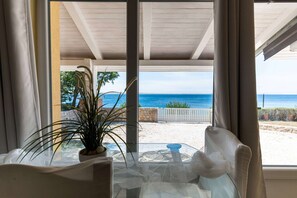 Una habitación con vistas a la playa, una mesa con sillas y una planta en maceta.