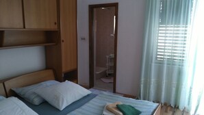 A bedroom with a bed, wooden wardrobe, and a bathroom visible through an open door. - Your Perfect Adriatic Getaway (Starigrad)