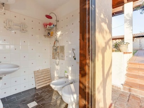 A bathroom with white tiled walls, a wooden door, a shower, a bidet, and a sink. - Villa in Partinico Near the Beach (Partinico)