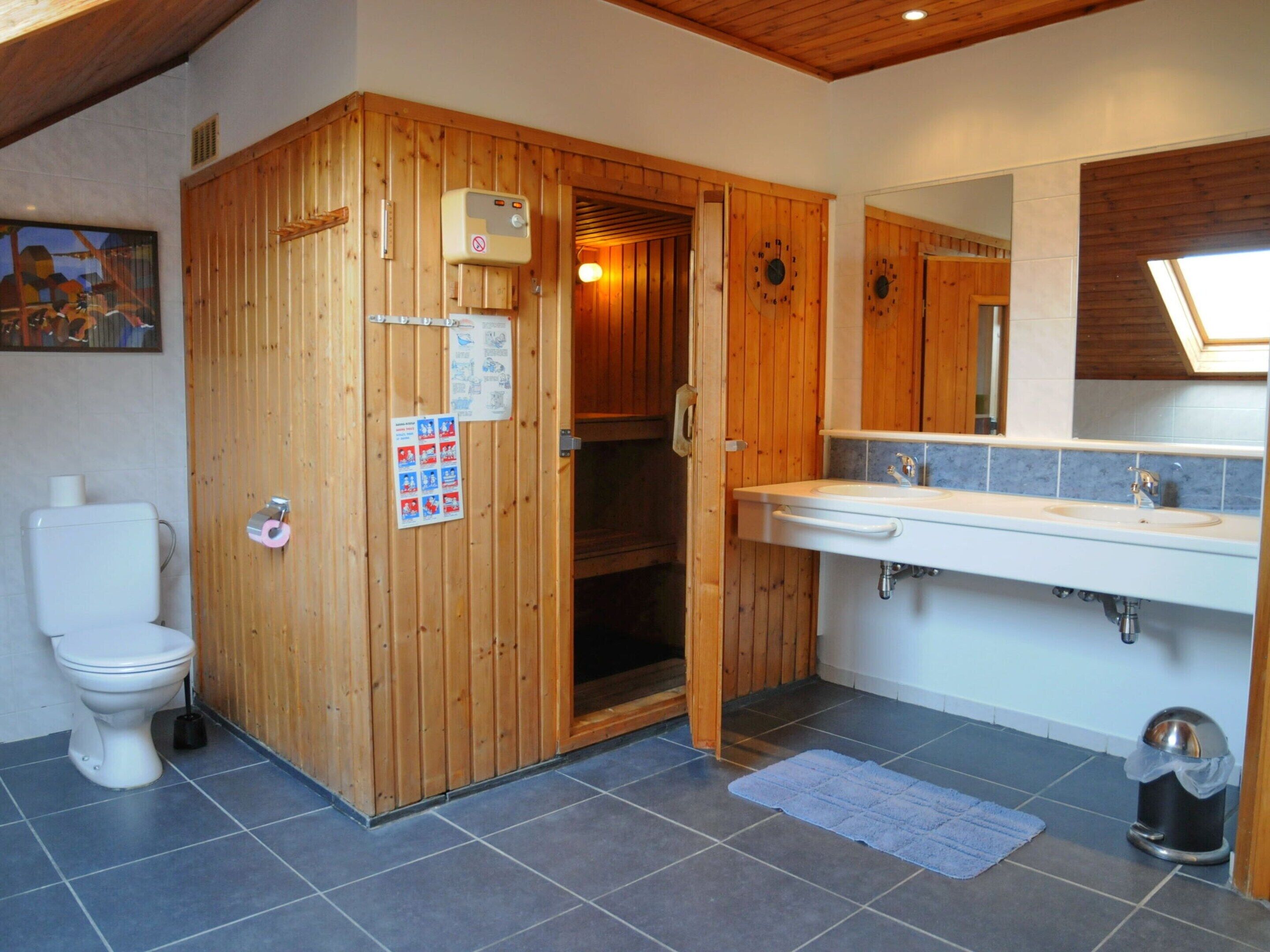 A bathroom with a wooden door, a white sink, and a toilet.