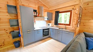 A compact kitchen with grey cabinets, a microwave, and a sink. There is a window with a view of greenery outside.