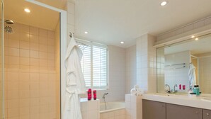 A modern bathroom with a bathtub, a shower, and a toilet. There are towels and toiletries on the counter. - Bungalow Near Marina and Beach Kamperland (Kamperland)