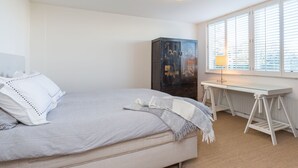 A bedroom with a bed, a desk, a radiator, and a window with blinds. - Bungalow Near Marina and Beach Kamperland (Kamperland)