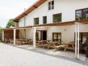 Un bâtiment doté d’un patio couvert, aménagé avec des tables et des chaises en bois pour pique-niquer.