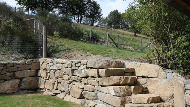 A stone wall structure with a grassy area in front. - Holiday Home in Ardennes With Sauna & Nature (Manhay)