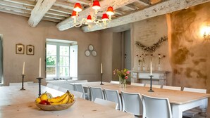 A dining area with wooden tables and white chairs, a chandelier, and a window with natural light. - Getaway With Sauna in Falaen (Onhaye)