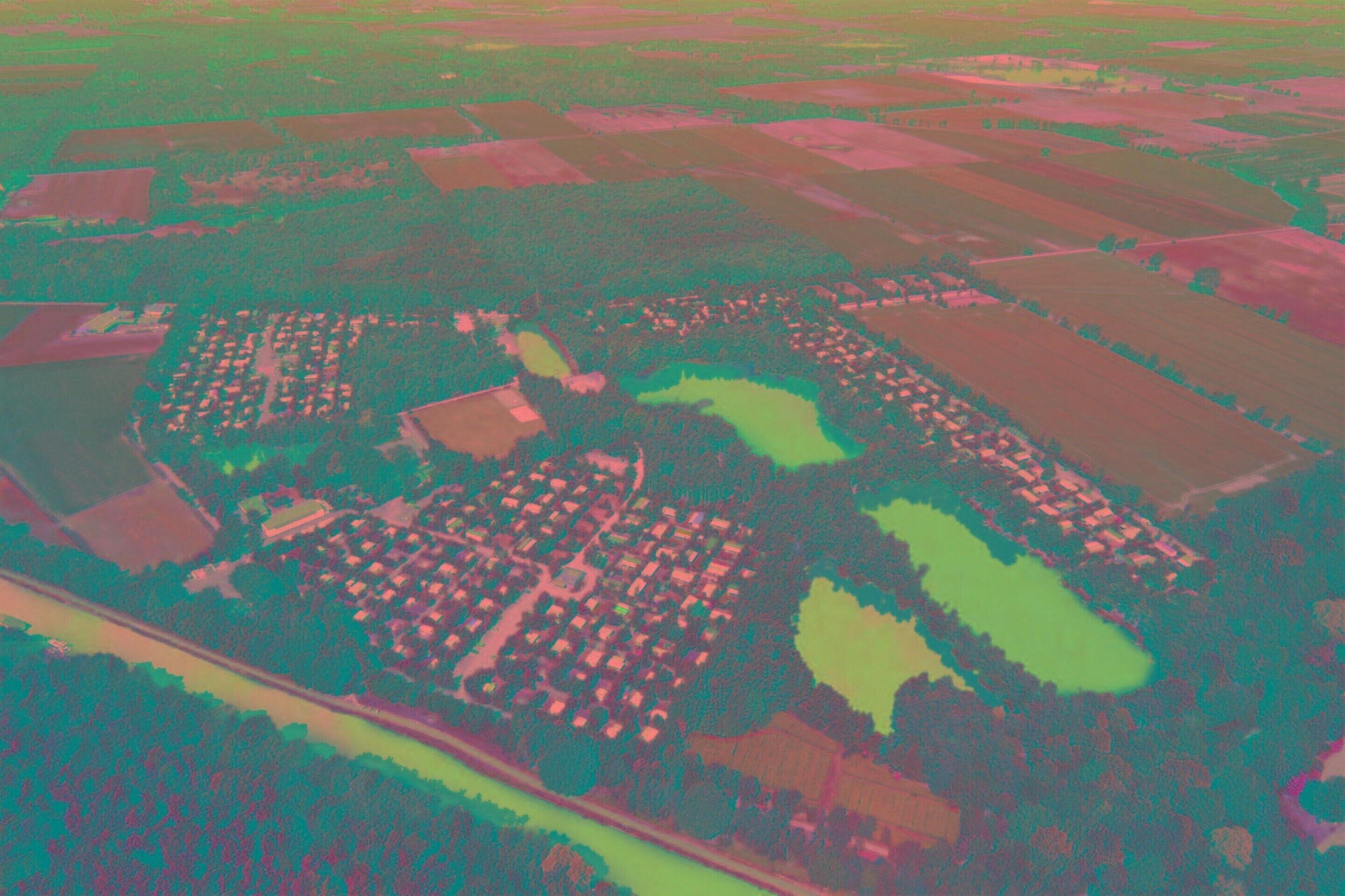 An aerial view of a residential area with distinct sections of houses, green spaces, and water bodies.