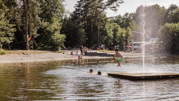 A water body with a fountain, surrounded by trees and a sandy area with people. - Chalet in Baalse Hei With Modern Comforts (Turnhout)
