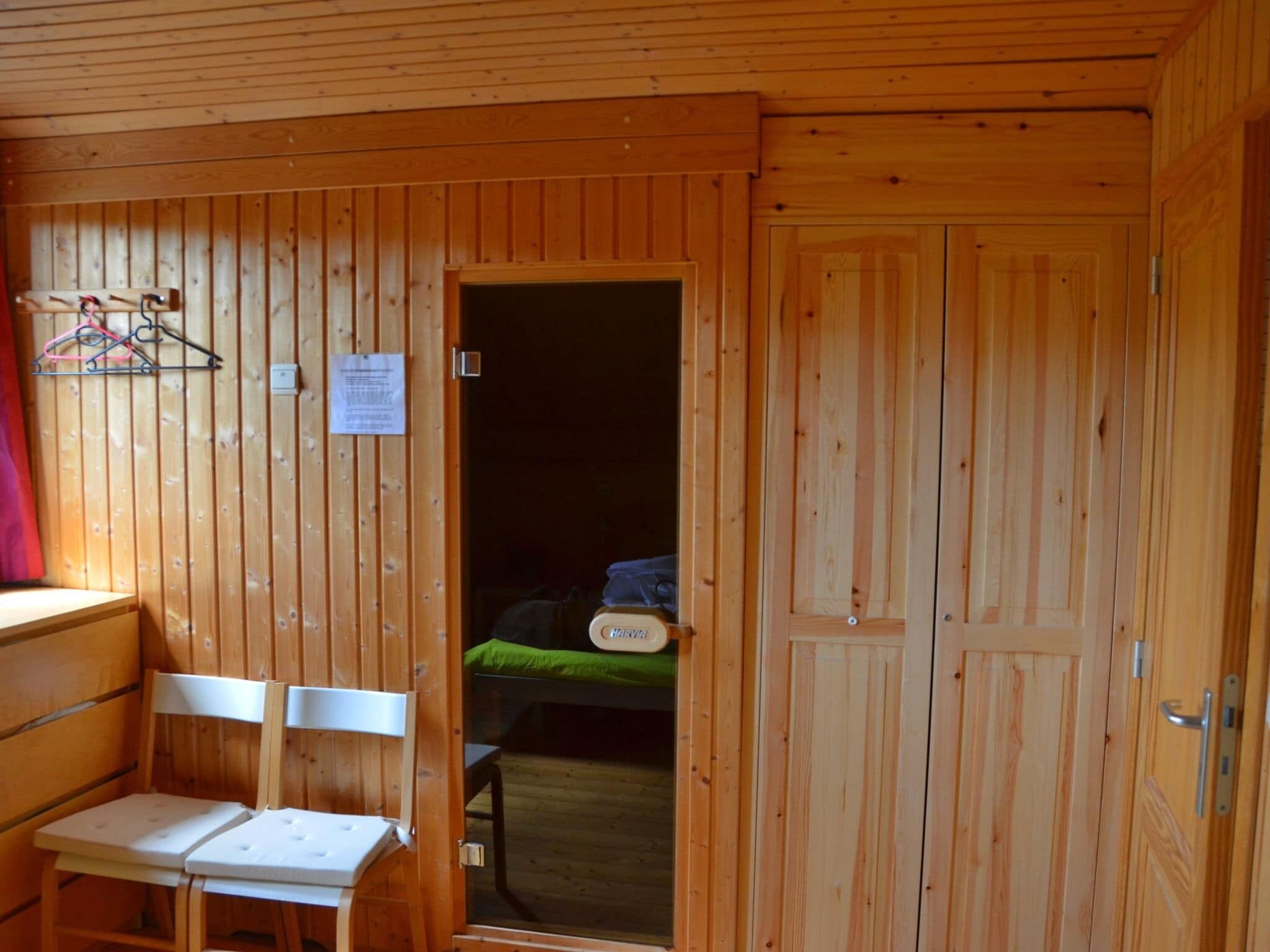 A wooden room with a bed, a desk, and a chair.
