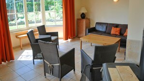Un salon avec un canapé, des fauteuils, une table et une lampe.