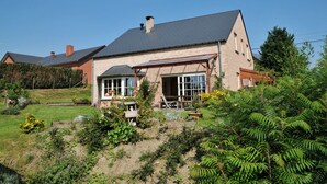 Une maison à deux étages, avec un toit en pente et une façade en briques.