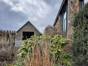 A stone building with a triangular roof and a wooden fence in the background. - Gîte L'olivier à Filly - Nadrin, Entre Houffalize et La Roche-en-ardenne (Houffalize)