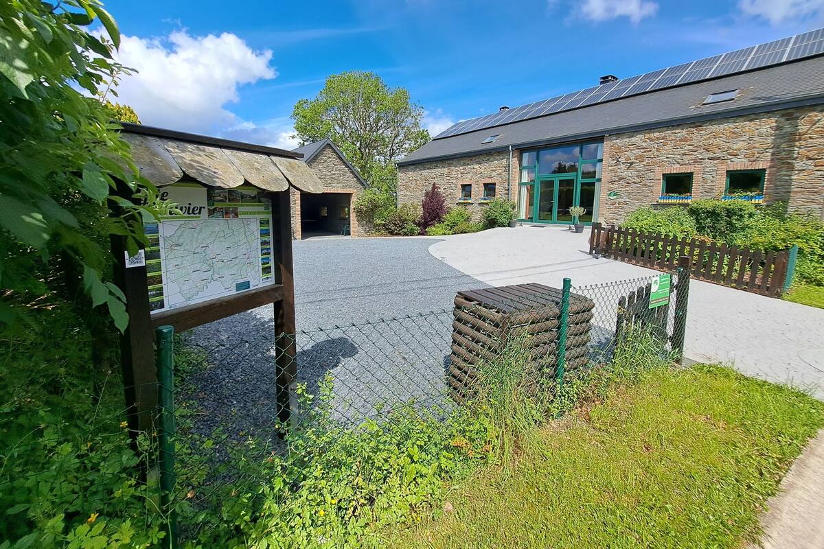 A stone building with a green door, a paved courtyard, and a signboard.