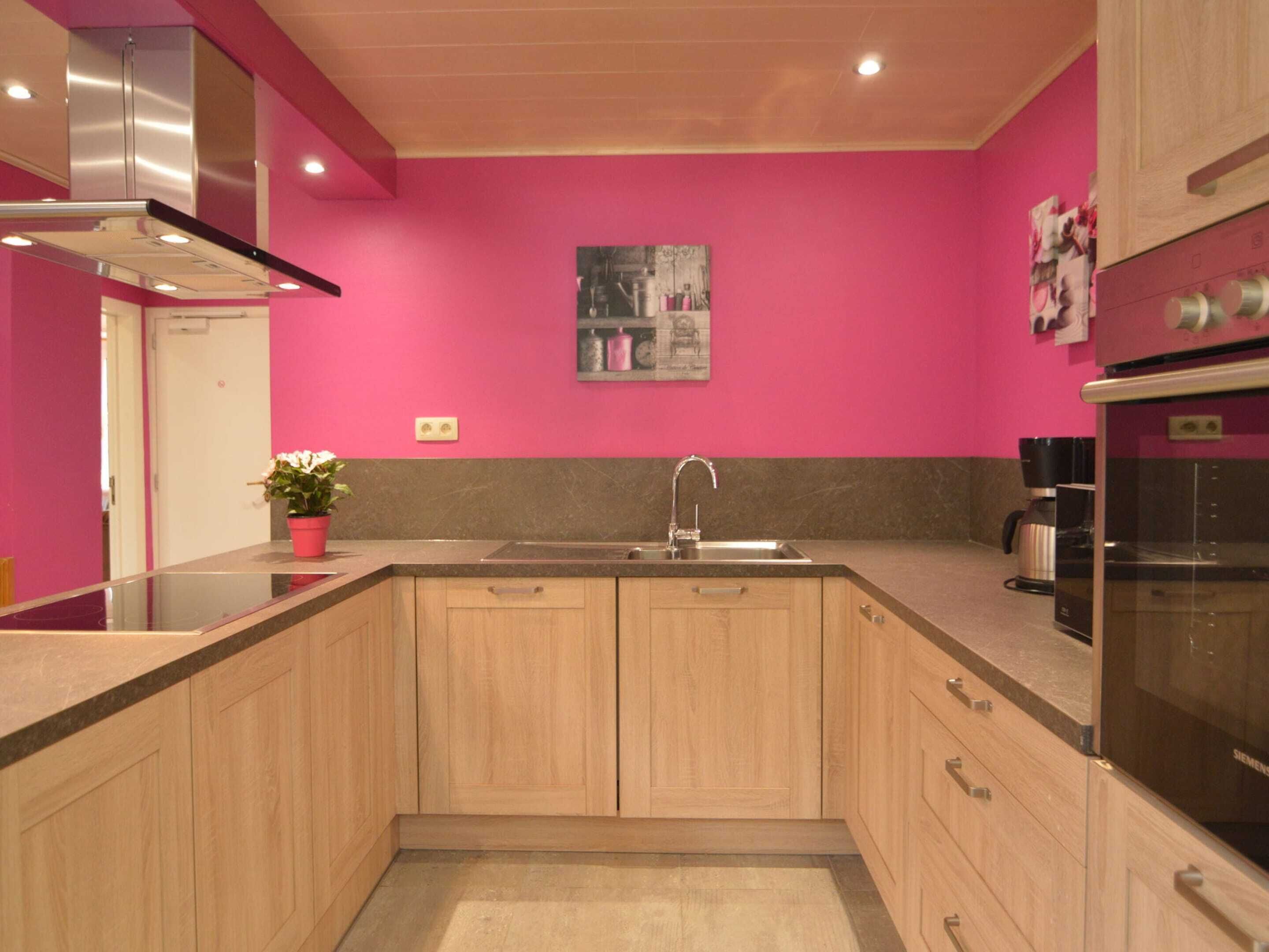 Een moderne keuken met houten kastjes, een roestvrijstalen spoelbak en een zwarte oven.