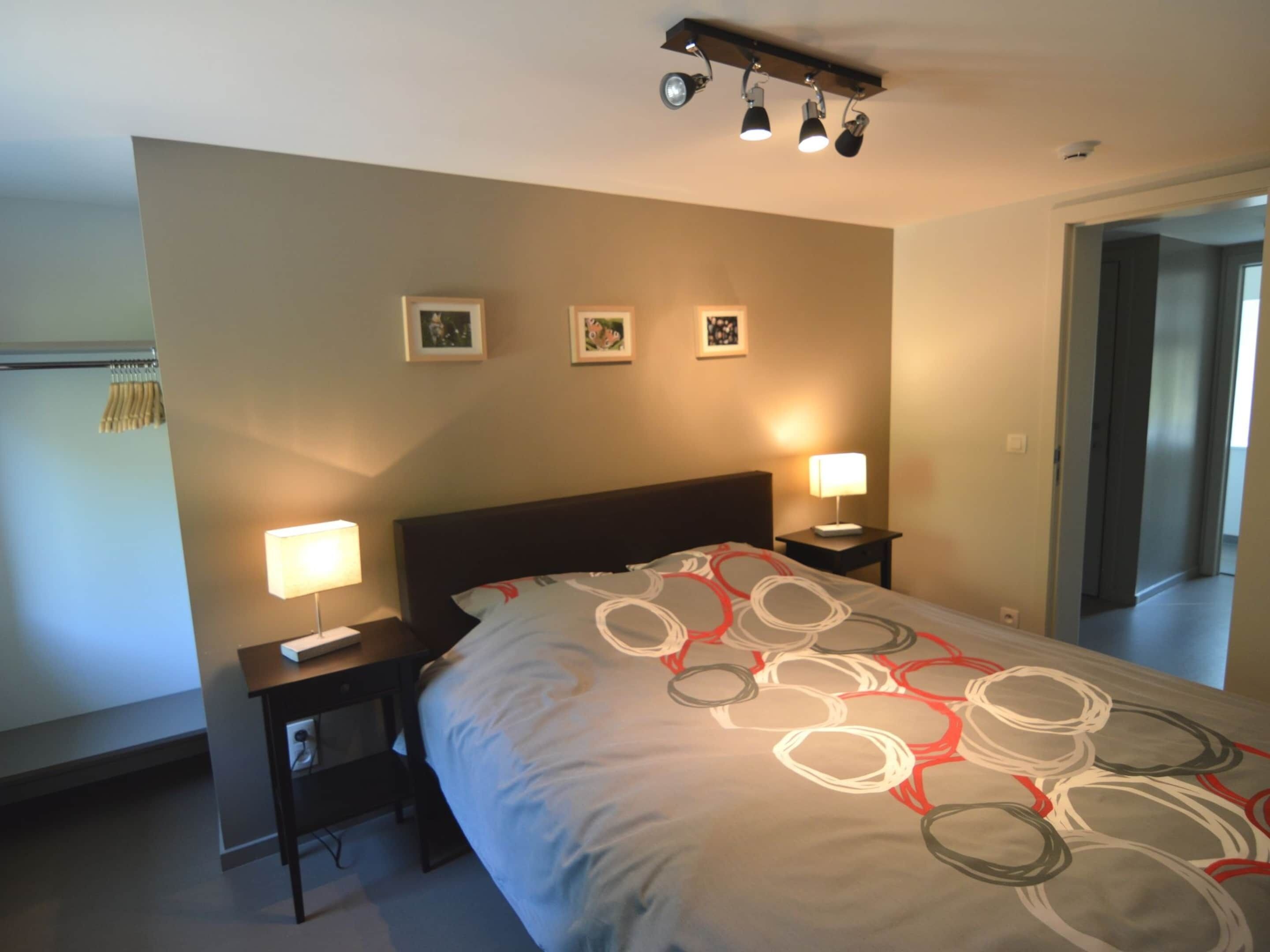 Una camera da letto con un letto, due comodini e tre luci a parete.