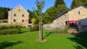 A stone building with a sloped roof and a small tree in front.