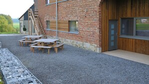 A brick building with a large wooden door, a staircase, and outdoor seating.