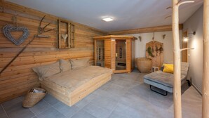 Quarto de madeira com uma cama, uma mesinha e um banco.