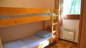 A bunk bed room with a radiator and a window with a view of trees. - Chalet in Belgium Surrounded by Nature (Viroinval)