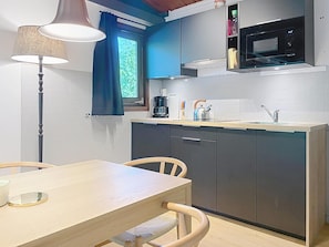 A compact kitchen with a microwave, kettle, and coffee maker. There is a dining table with chairs and a lamp. - Chalet in Belgium Surrounded by Nature (Viroinval)