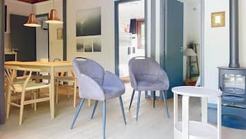Um interior moderno com área de refeições, duas cadeiras, uma mesa e uma pequena mesa branca.