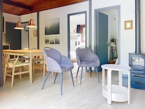 A modern interior with a dining area, two chairs, a table, and a small white table. - Chalet in Belgium Surrounded by Nature (Viroinval)