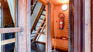 Interior em madeira com escada, um extintor de incêndio e uma porta.