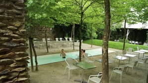 Una terrazza esterna con sedie e tavoli in metallo bianco, un muro in pietra e una zona piscina.