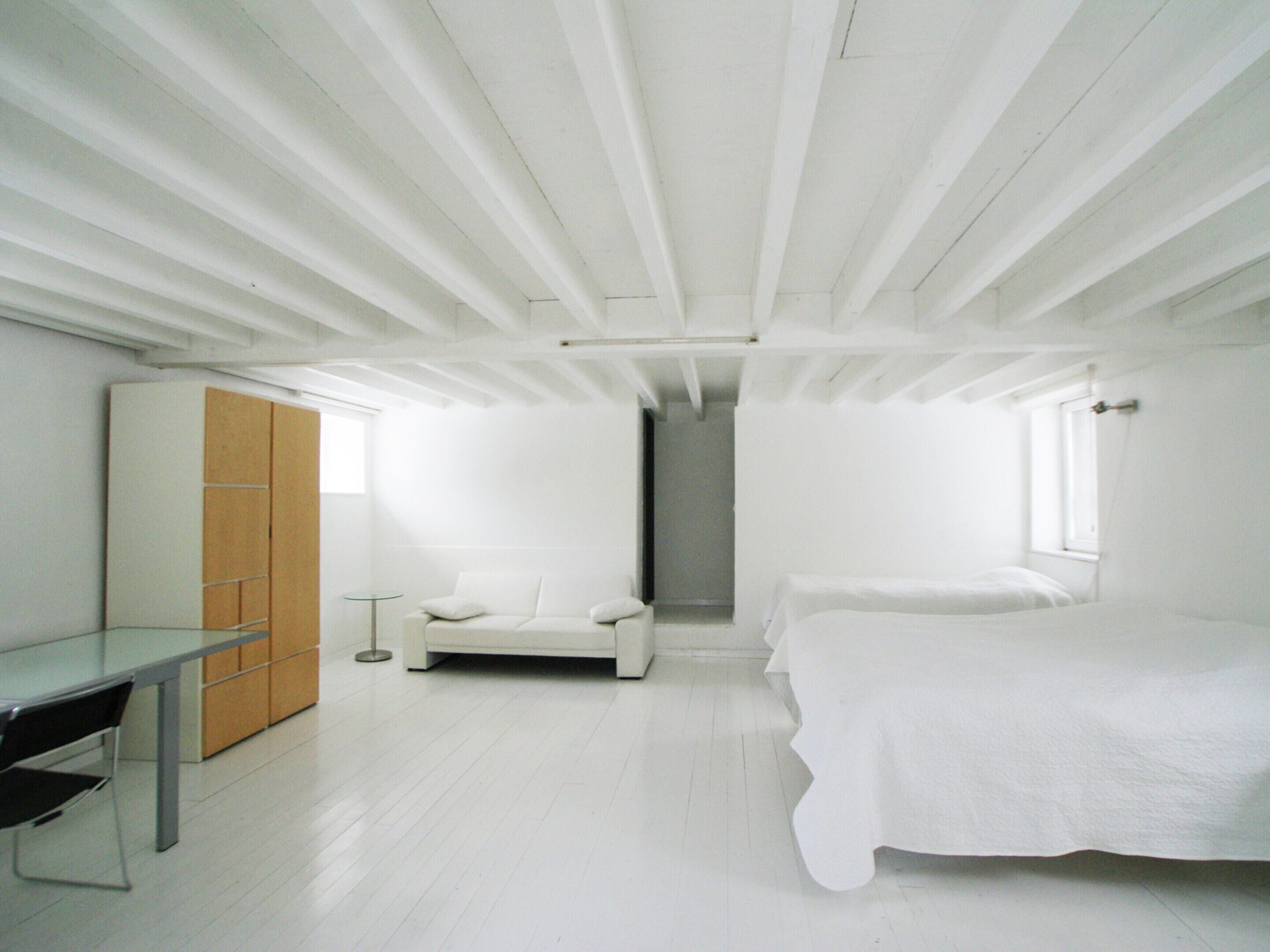 A modern bedroom with a bed, a chair, a desk, and a wardrobe.