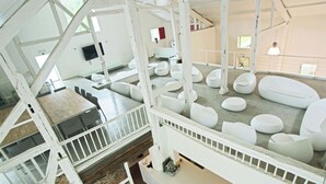 Un interno moderno con soffitto alto, travi strutturali bianche e diverse disposizioni di posti a sedere.