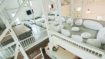 A modern interior with a high ceiling, white structural beams, and a variety of seating arrangements.