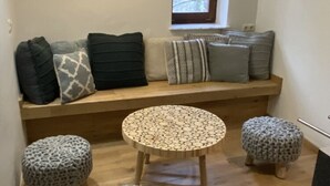 A cozy seating area with a wooden bench, patterned cushions, and two knitted stools. - Holiday Home in Semois Valley Near Kayaking (Vresse-sur-Semois)