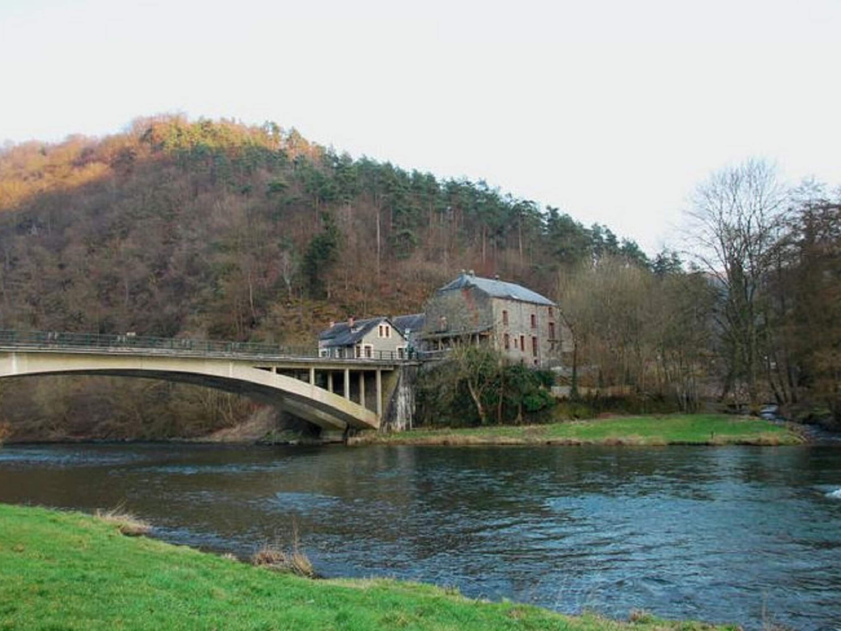 Un ponte di pietra sopra un fiume, con un edificio sulla riva destra.
