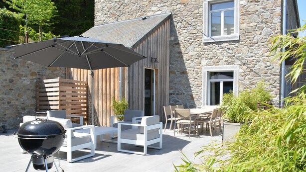 A patio with a grill, outdoor furniture, and a stone building in the background. - Cozy Holiday Home in Gedinne near Forest (Gedinne)