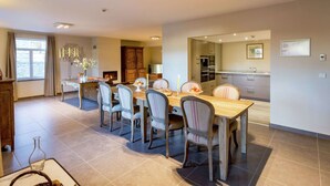 A spacious dining area with a wooden table and six chairs, a kitchen with modern appliances, and a fireplace. - Cozy Holiday Home in Gedinne near Forest (Gedinne)