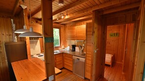 A wooden cabin interior with a kitchen, dining area, and a sleeping area. - Chalet in Durbuy With Jacuzzi & Garden (Somme-Leuze)